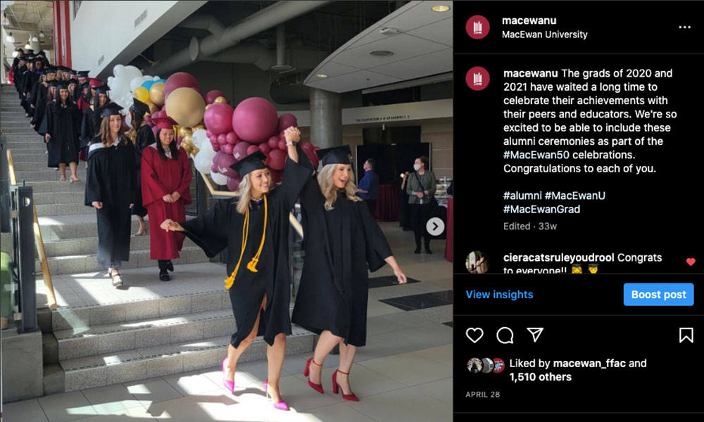 Grads walk down the staircase in Building 9 in caps and gowns, surrounded by balloons